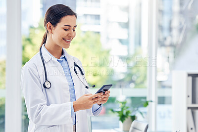 Buy stock photo Shot of a young doctor using a cellphone in a hospital