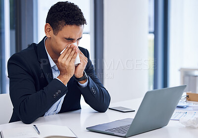 Buy stock photo Shot of a young businessman blowing his nose while working in an office