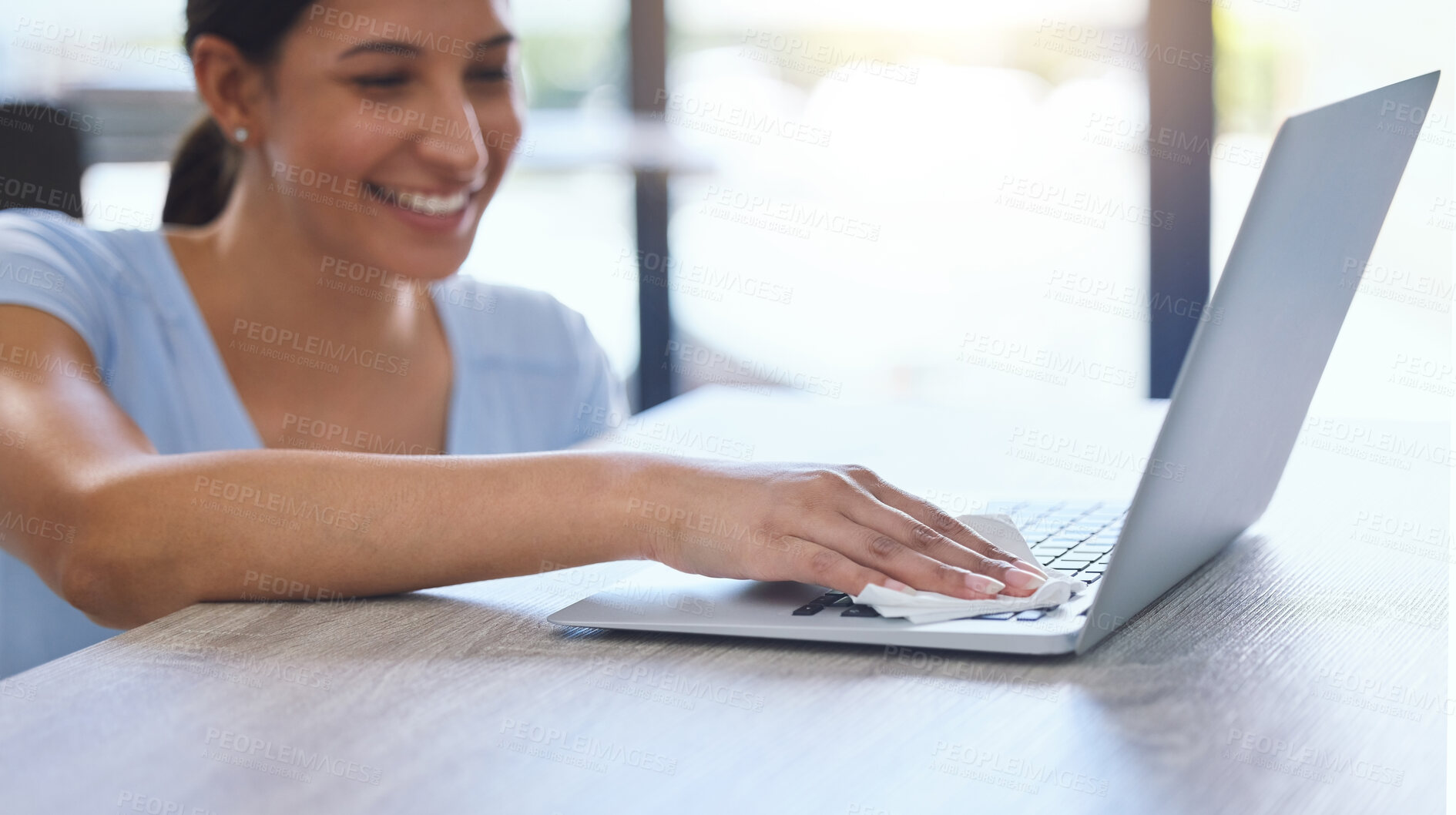 Buy stock photo Shot of a beautiful young woman carefully cleaning a laptop at home