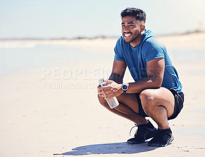 Buy stock photo Shot of a man holding a water water while taking a break during a workout on the beach