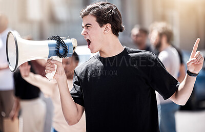 Buy stock photo Shot of a young man yelling through a megaphone during a protest