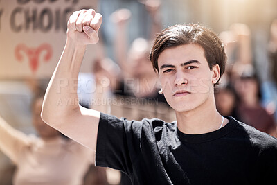 Buy stock photo Shot of a young man with his fist raised at a protest rally