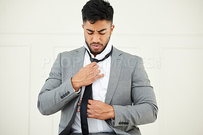 Buy stock photo Cropped shot of a handsome young businessman tying his tie while getting ready for work