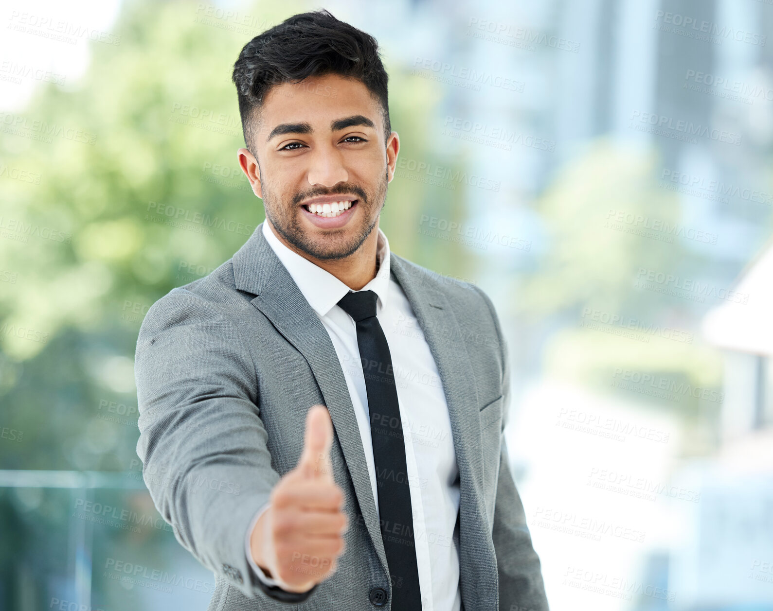 Buy stock photo Cropped portrait of a handsome young businessman reaching out for a handshake while standing in his office