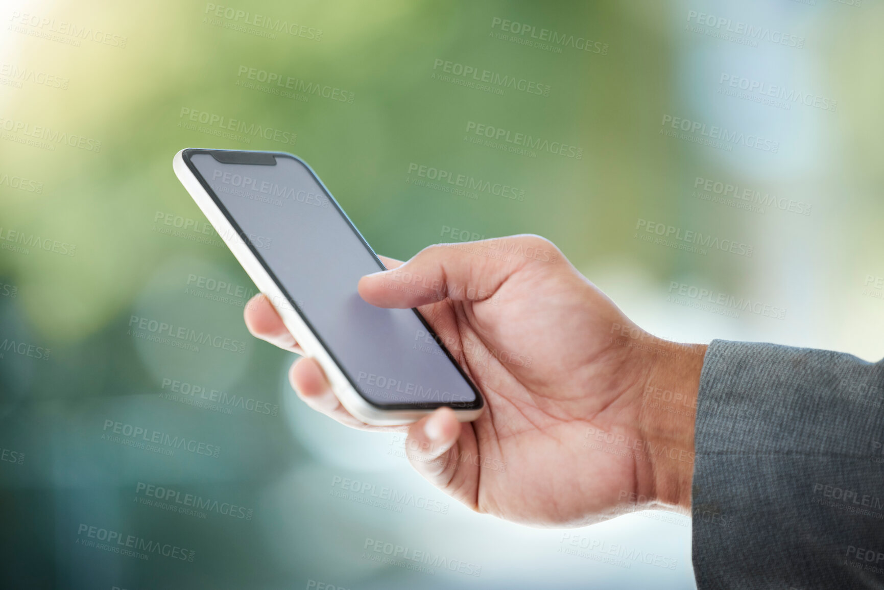 Buy stock photo Cropped shot of an unrecognizable businessman using his cellphone while standing in the office