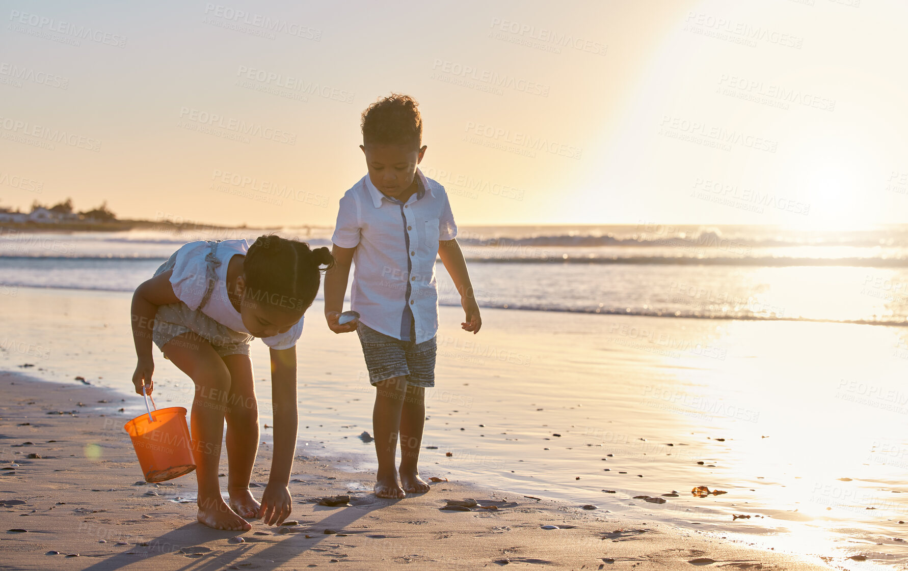 Buy stock photo Children, beach and playing together at sunset, collect rocks and shore for holiday bonding. Kids, brother and sister walking on sand for vacation fun, weekend trip and travel to coast for adventure