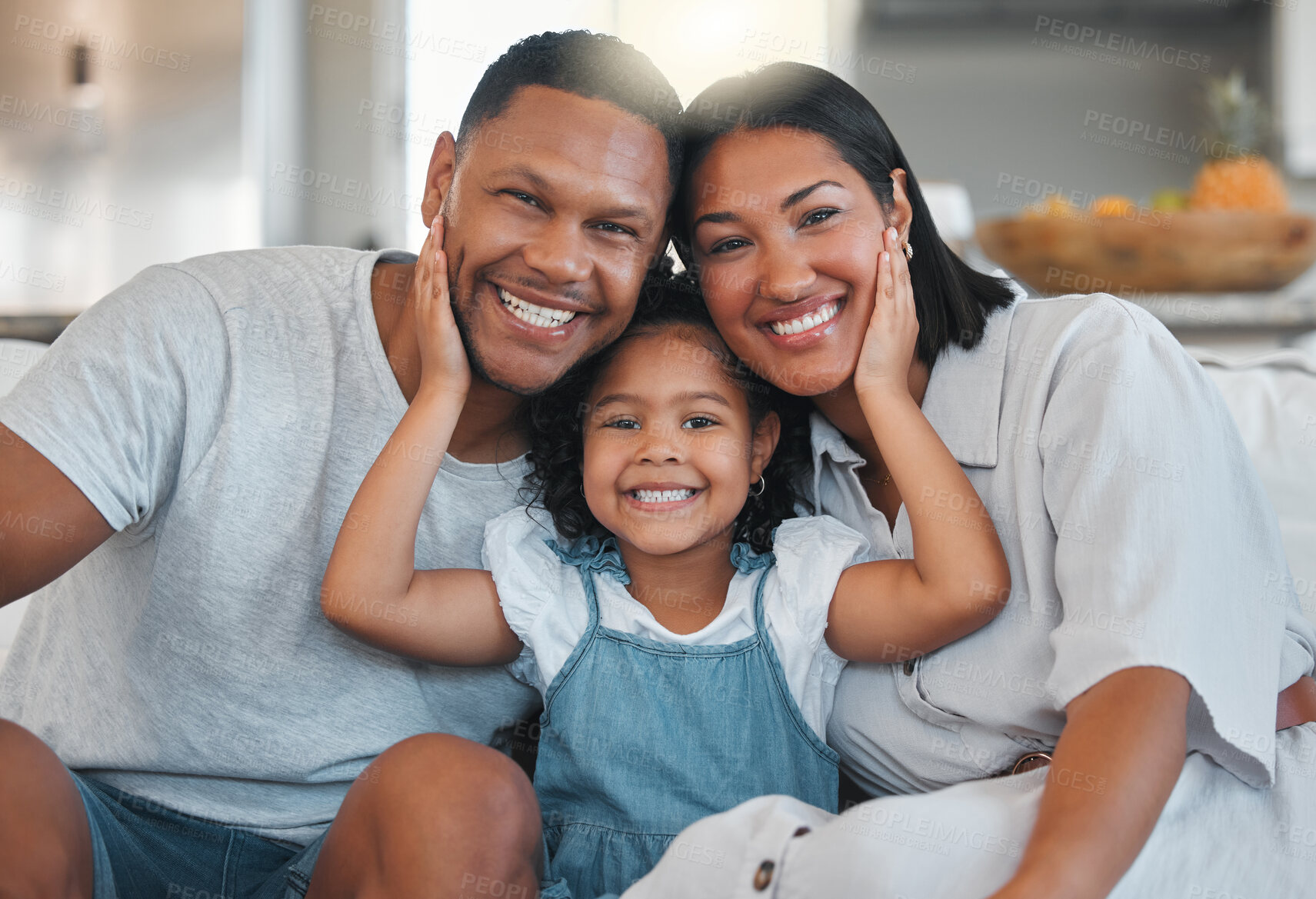 Buy stock photo Shot of a young family bonding with their daughter on the sofa at home