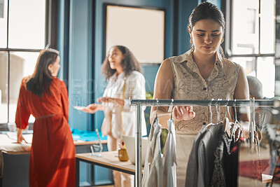 Buy stock photo Shot of a young woman sorting through clothes at a boutique
