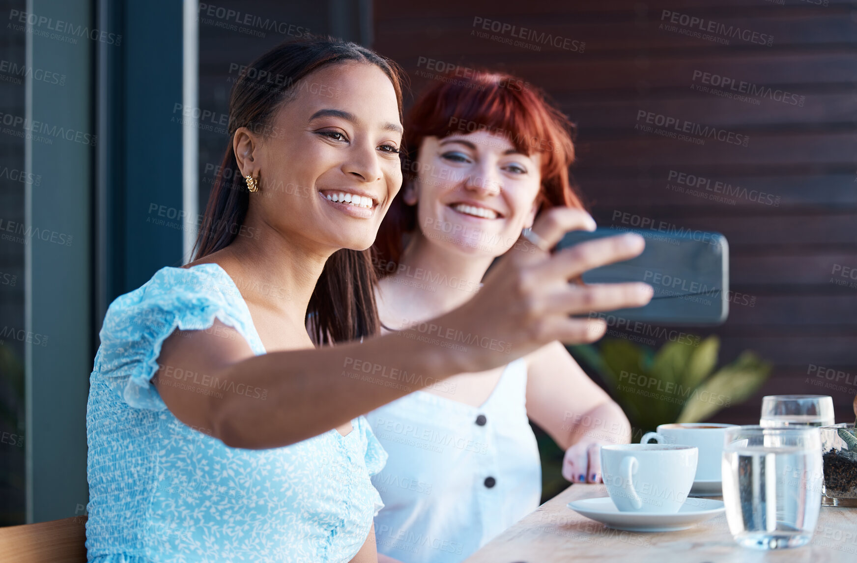 Buy stock photo Shot of two young female friends taking a selfie at a cafe