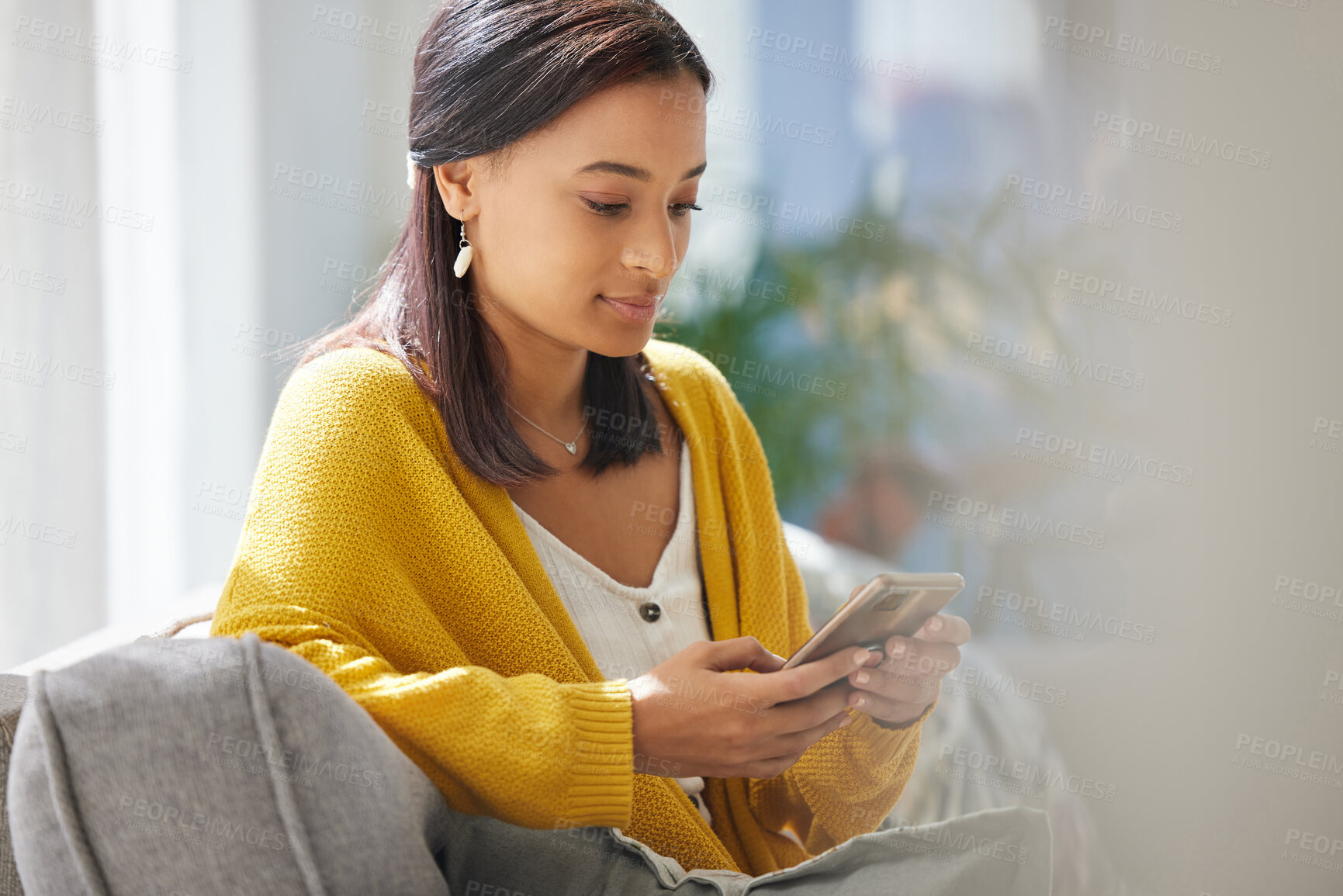 Buy stock photo Shot of a young woman using a phone at home