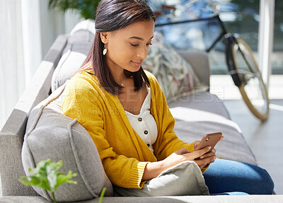 Buy stock photo Shot of a young woman using a phone at home