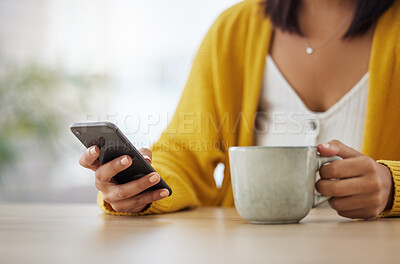 Buy stock photo Shot of a young woman drinking coffee while using a phone at home