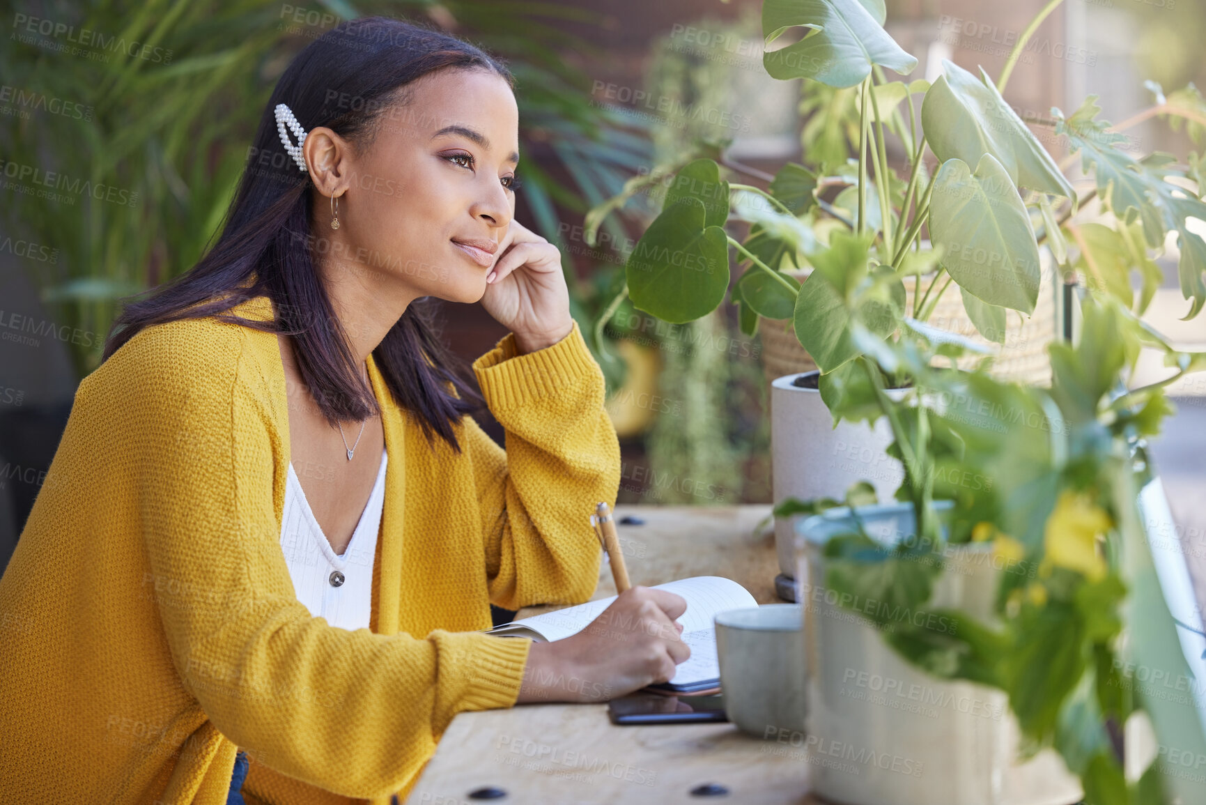 Buy stock photo Shot of a young businesswoman writing in a notebook while working on the balcony at home