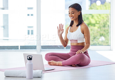 Buy stock photo Shot of a sporty young woman having a video call on a laptop in a yoga studio