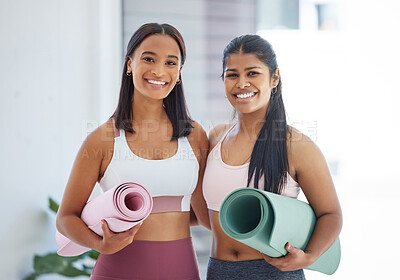 Buy stock photo Portrait of two sporty young women holding exercise mats in a yoga studio