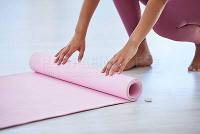 Buy stock photo Closeup shot of an unrecognisable woman rolling an exercise mat on the floor in a yoga studio