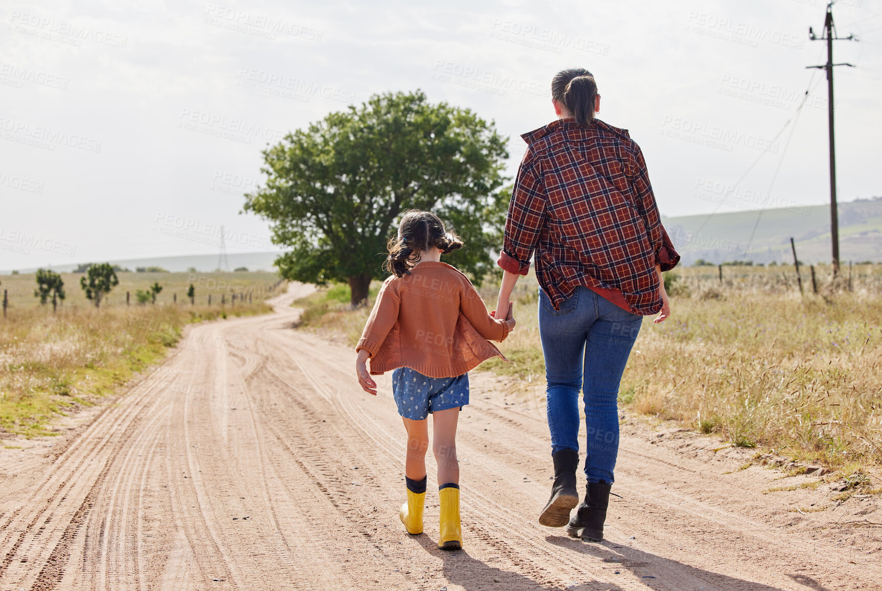 Buy stock photo Rearview shot of a little girl holding her mother's hand while walking on a farm