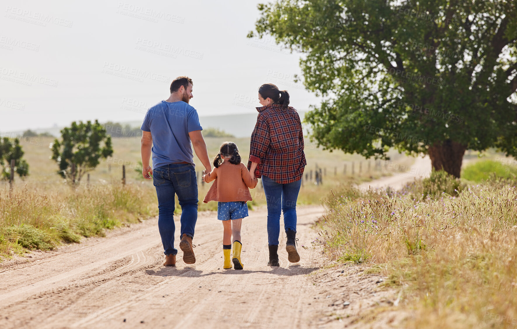 Buy stock photo Holding hands, parents and walking with kid on farm for love, care and support with family on dirt road. Back, mother and father with girl in countryside to travel together, holiday and agriculture