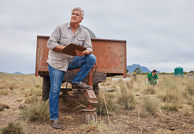 Buy stock photo Shot of a farmer writing notes on a clipboard