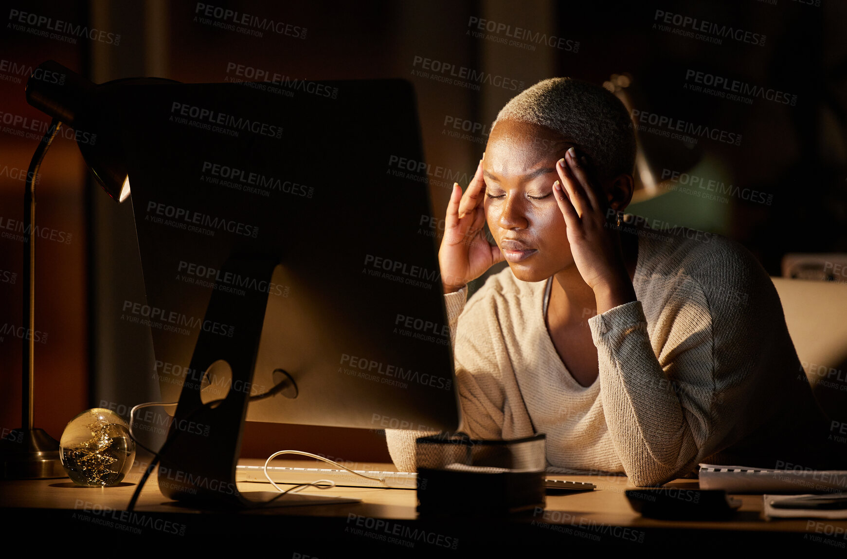 Buy stock photo Shot of a young businesswoman looking stressed out while working on a computer in an office at night