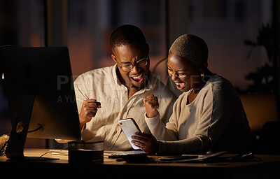 Buy stock photo Shot of two businesspeople cheering while working together in an office at night