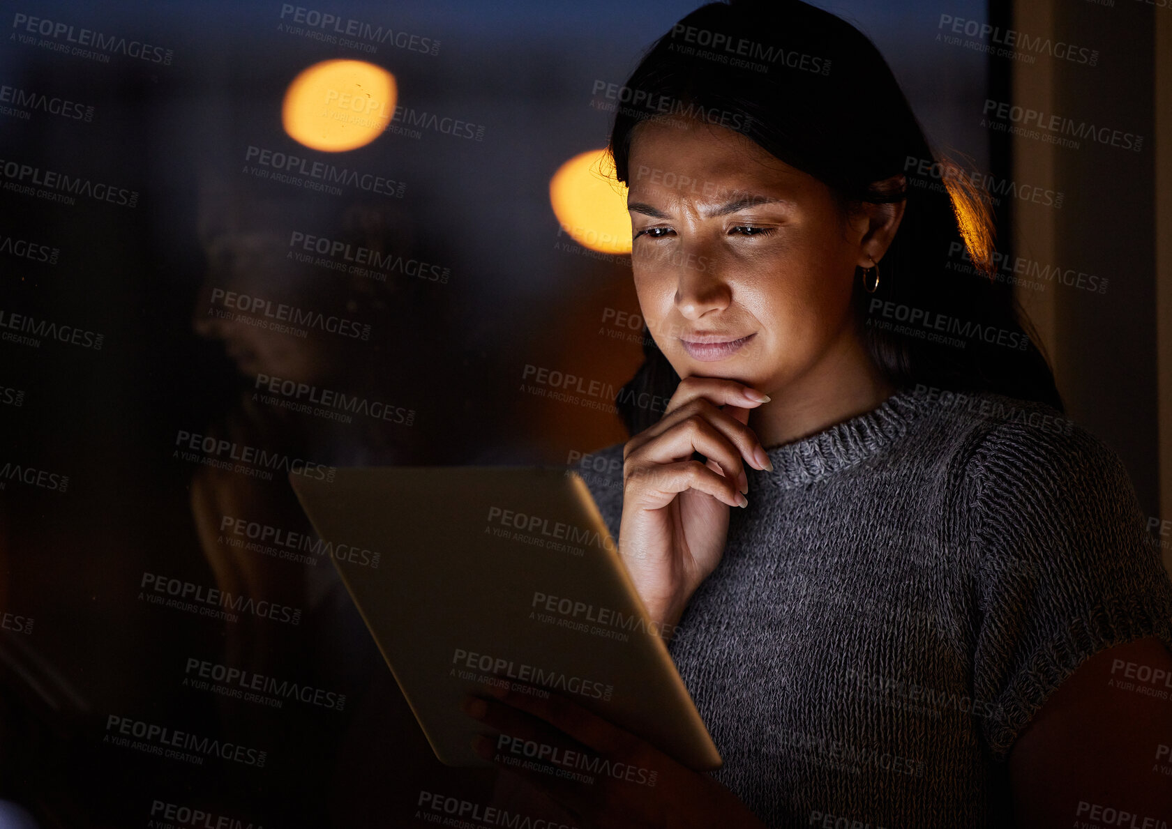 Buy stock photo Shot of a young businesswoman looking thoughtful while using a digital tablet in an office at night