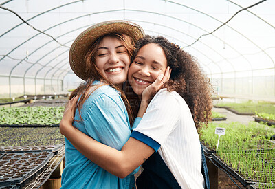 Buy stock photo Cropped shot of two attractive young women hugging while working in a greenhouse on a farm