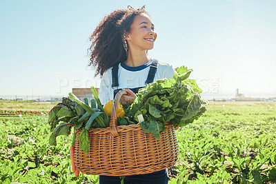 Buy stock photo Shot of a young farmer holding a basket of freshly harvested veggies