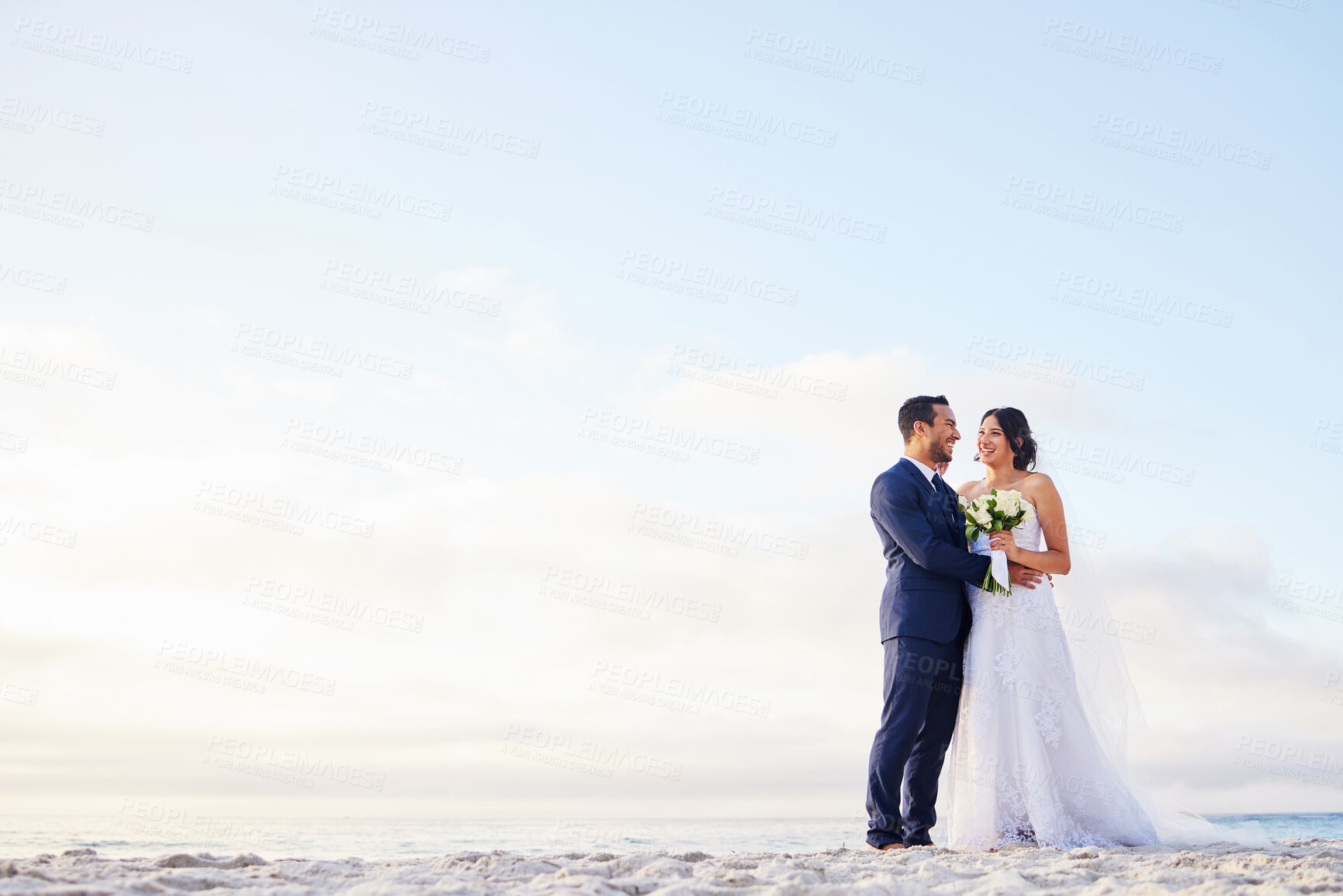 Buy stock photo Shot of a young couple on the beach on their wedding day