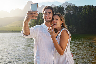 Buy stock photo Couple, nature selfie and engagement by lake for celebration, happiness and excited for future. Man, woman and photography for social media, profile picture and romance with love, proposal and goals