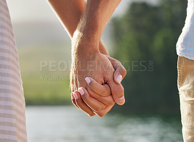 Buy stock photo Holding hands, love and couple at lake outdoors for commitment, trust and support. Romantic date, care and woman and man together for romance, bonding and affection with soulmate at creek on vacation