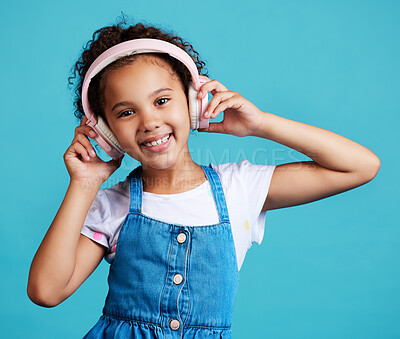 Buy stock photo Music, portrait and girl child with headphones in studio for streaming, subscription and audio on blue background. Face, autism and autistic kid happy with noise canceling headphone while isolated