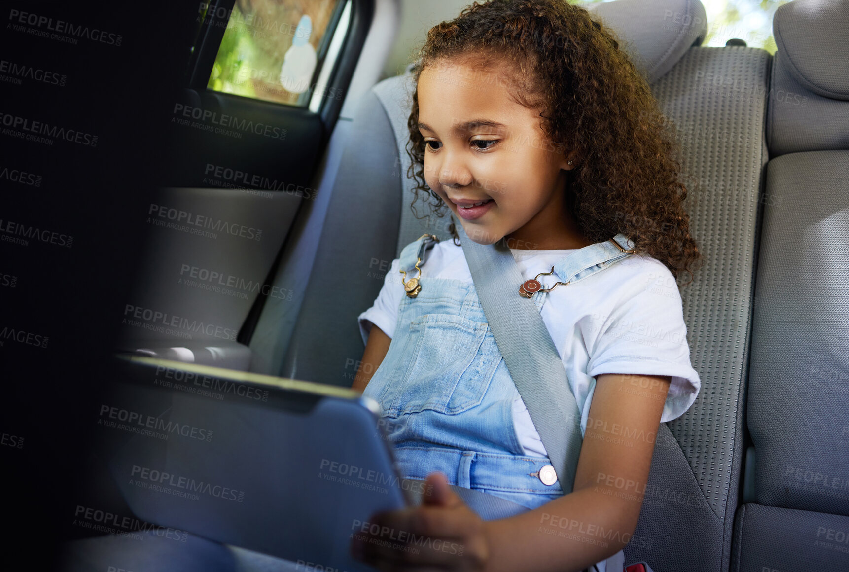 Buy stock photo Child in car, tablet and video on road trip with seatbelt for safety and device to play educational online game. Technology, internet browsing and travel, happy girl on backseat for drive or carpool.