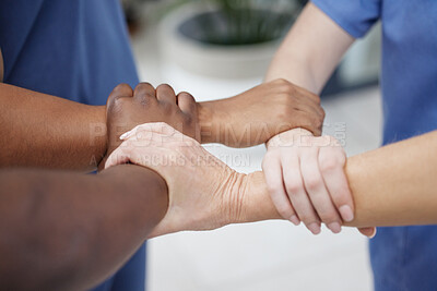 Buy stock photo Shot of a group of unrecognizable doctors linking arms at a hospital