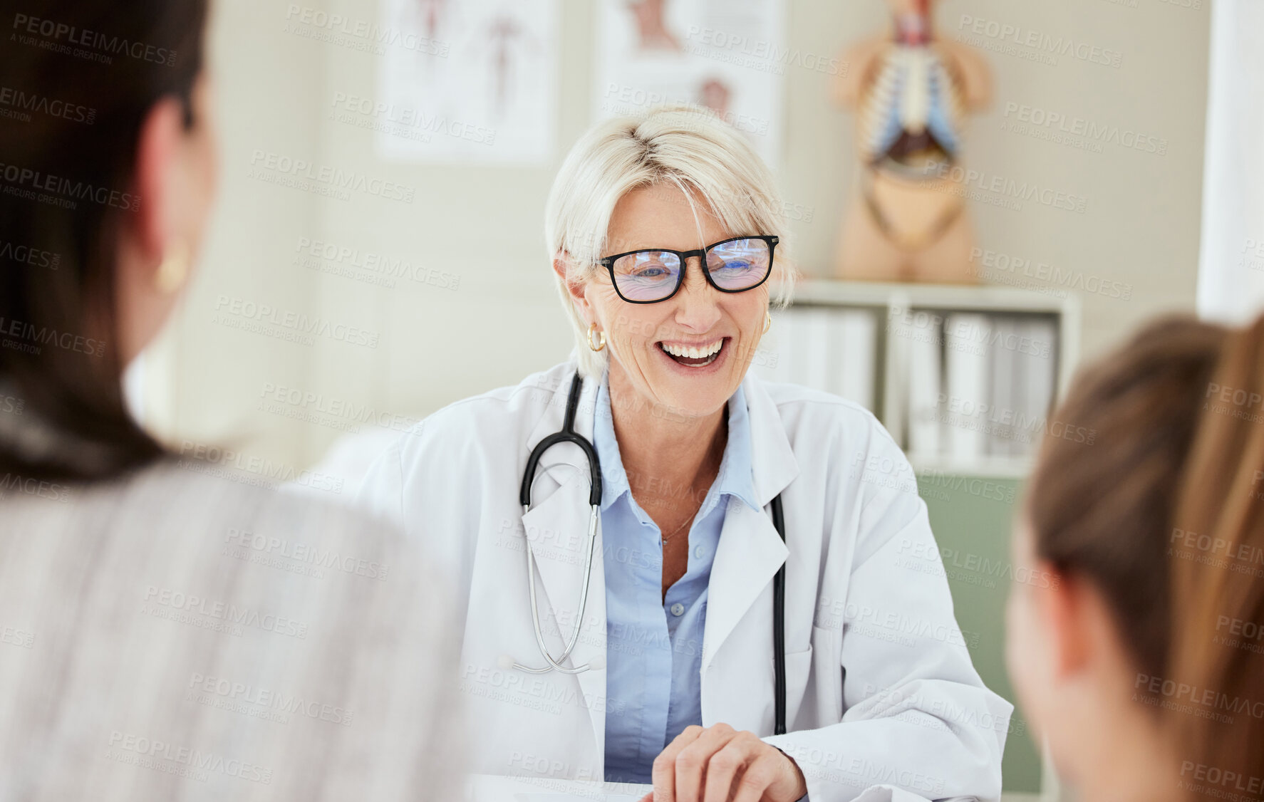 Buy stock photo Checkup, doctor and talking to child, laughing and mature woman with glasses, growth and development. Office, mom and diagnosis in appointment and conversation for health of kid and pediatrician