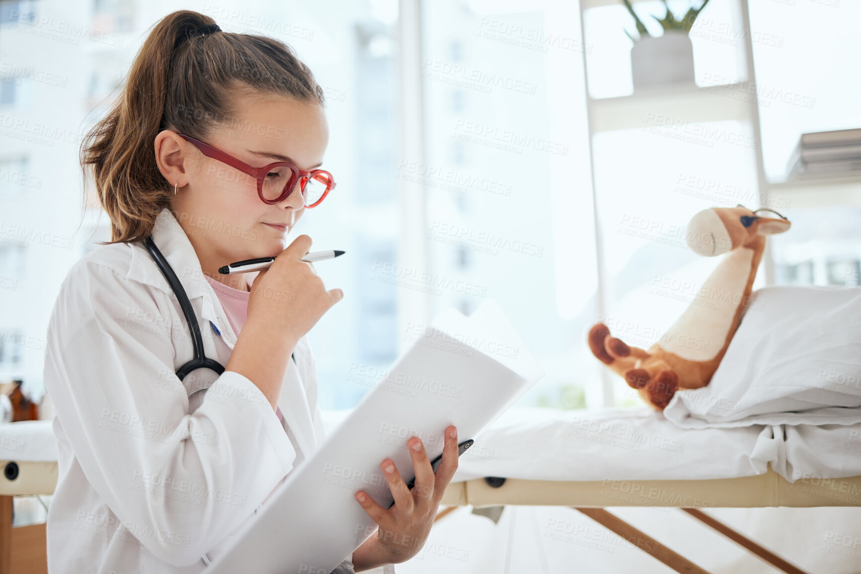 Buy stock photo Shot of a little girl pretending to be a doctor while examining her stuffed animal at home