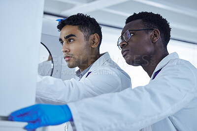 Buy stock photo Shot of two lab workers removing samples from a storage facility