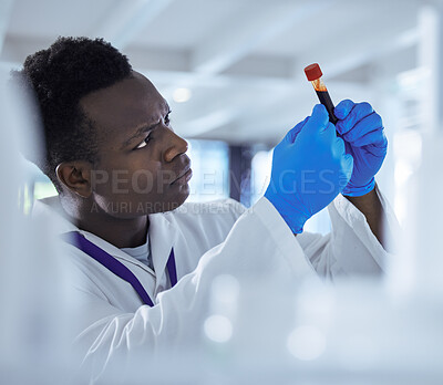 Buy stock photo Shot of a young male scientist analysing a blood sample in a test tube