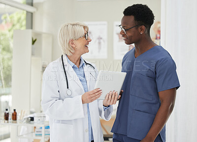 Buy stock photo Shot of two medical doctors having a discussion while using a digital tablet