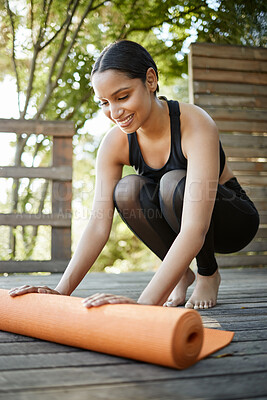 Buy stock photo Full length shot of an attractive young female athlete rolling out her yoga mat outdoors