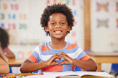 Buy stock photo Shot of a preschool student forming a heart shape with his hands while sitting in class