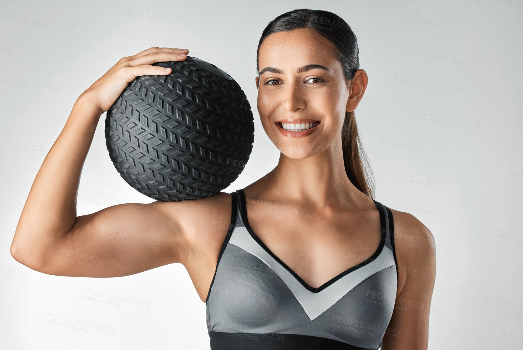 Buy stock photo Studio portrait of a sporty young woman holding a medicine ball against a grey background