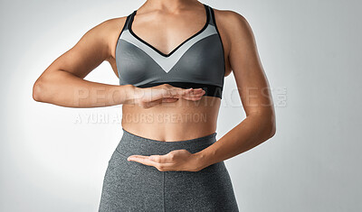 Buy stock photo Studio shot of an unrecognisable woman framing her stomach with her hands against a grey background