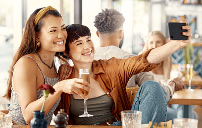 Buy stock photo Shot of two friends taking selfies using a smartphone at a restaurant