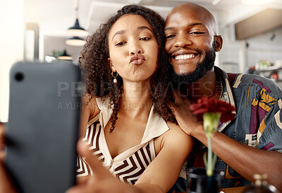 Buy stock photo Shot of a young couple on a date at a restaurant taking selfies using a cellphone