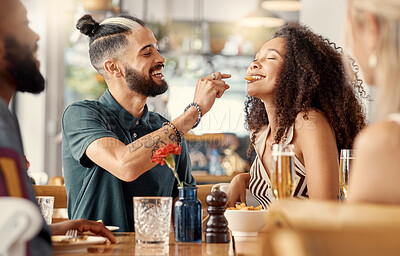 Buy stock photo Shot of a young man feeding his girlfriend fries in a restuarant