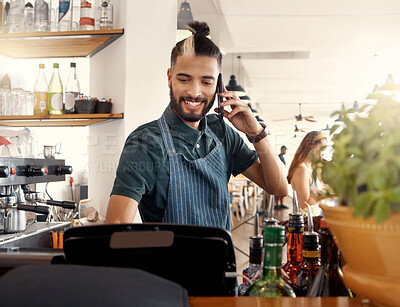 Buy stock photo Shot of a young waiter making a phone call on his smartphone while placing an order