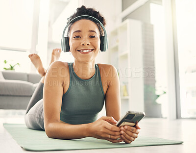 Buy stock photo Yoga, portrait and happy woman relax on a living room floor with music, headphones and phone for streaming at home. Face, smile and lady on fitness break with social media, radio or podcast in lounge