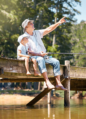 Buy stock photo Grandfather, child and pointing while fishing at lake for fun hobby, adventure and teaching about nature. Boy kid, view and learning to fish with senior man at river, camping trip and happy vacation 