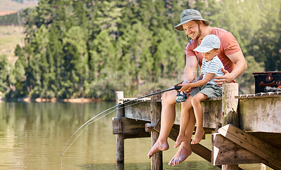 Buy stock photo Shot of a little boy fishing with his father at a lake in a forest